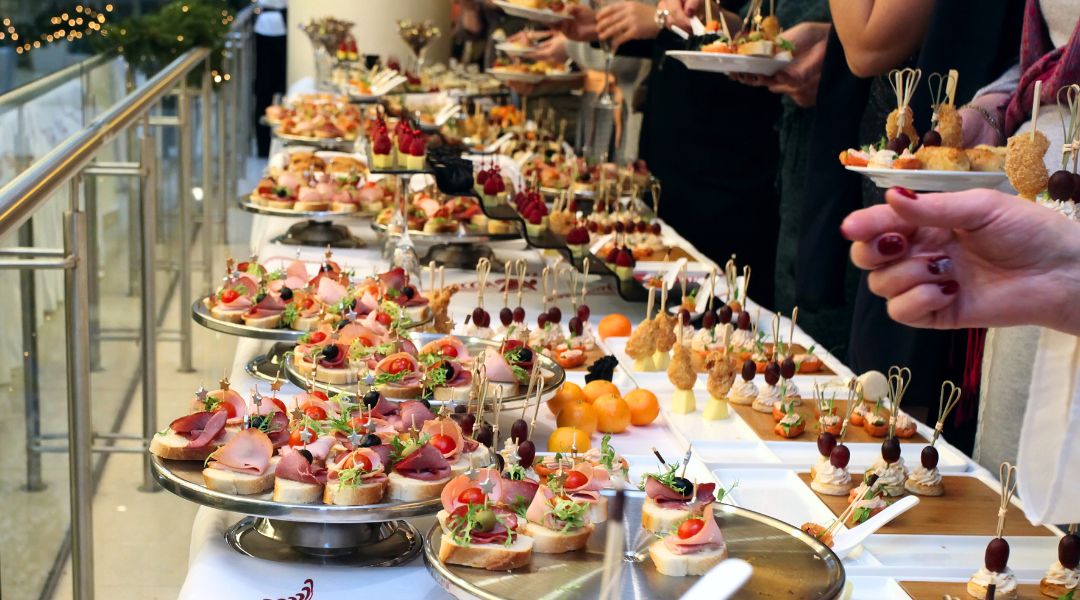 A lavish buffet with assorted appetizers, including meats, cheeses, fruits, and decorative garnishes, at an event