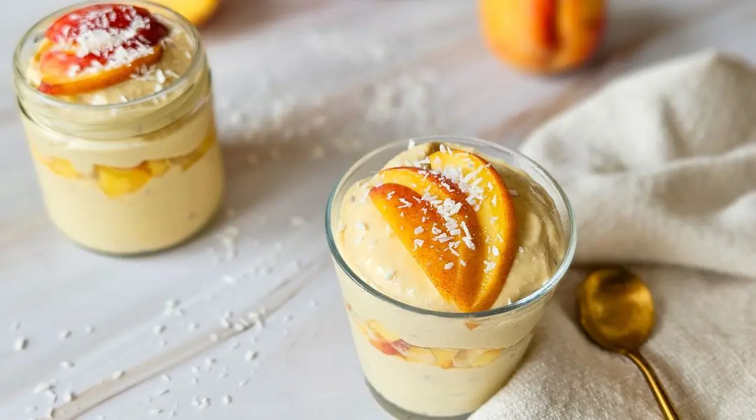 Peach and mango mousse cups topped with fresh peach slices and shredded coconut
