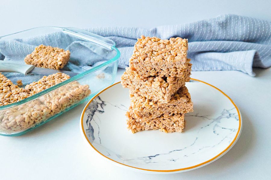 Three stacked squares of crispy rice treats on a marble-patterned plate