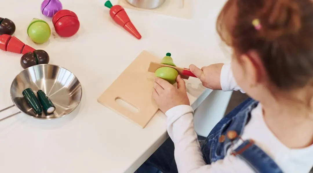Child playing with wooden vegetables on a cutting board