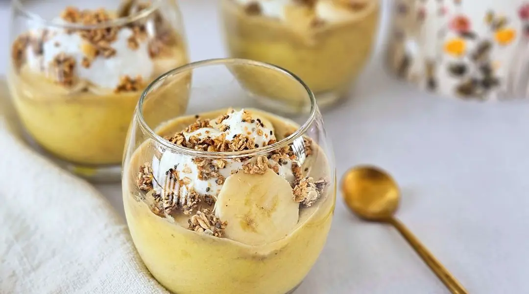 Banana pudding in a glass, topped with granola and banana slices
