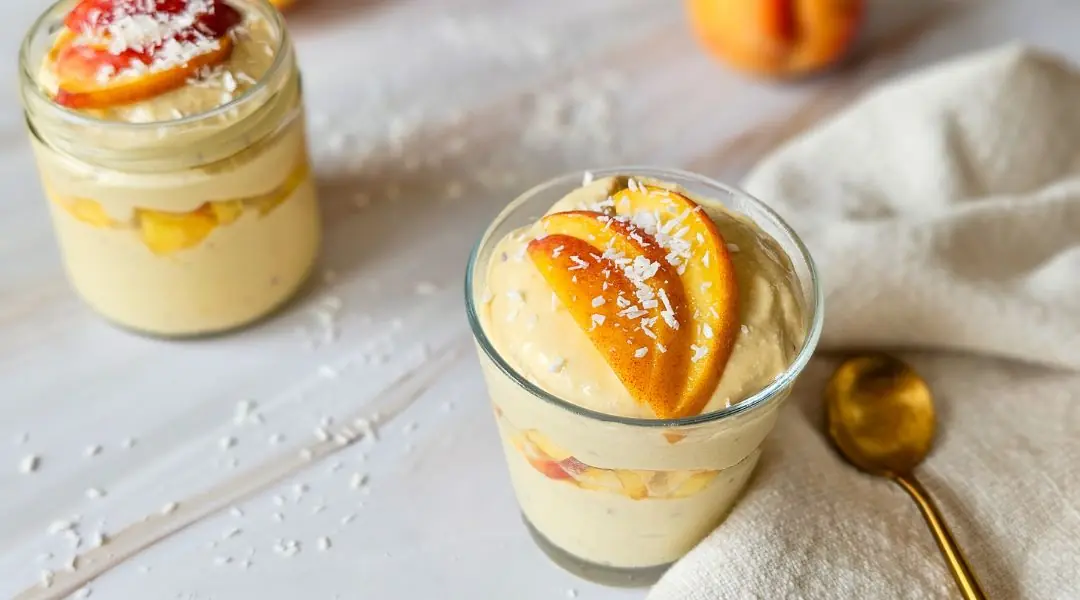Mango mousse in a glass topped with coconut and fresh fruit