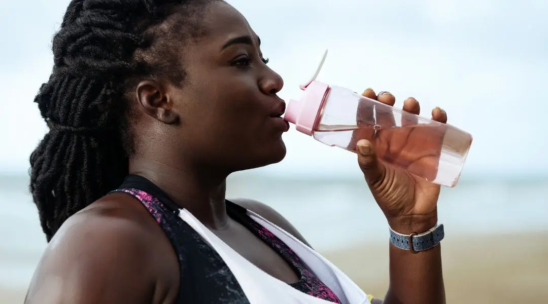 Woman hydrating with a water bottle after exercise.