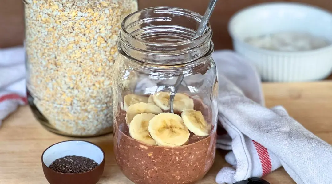 Mason jar filled with chocolate overnight oats, topped with banana slices