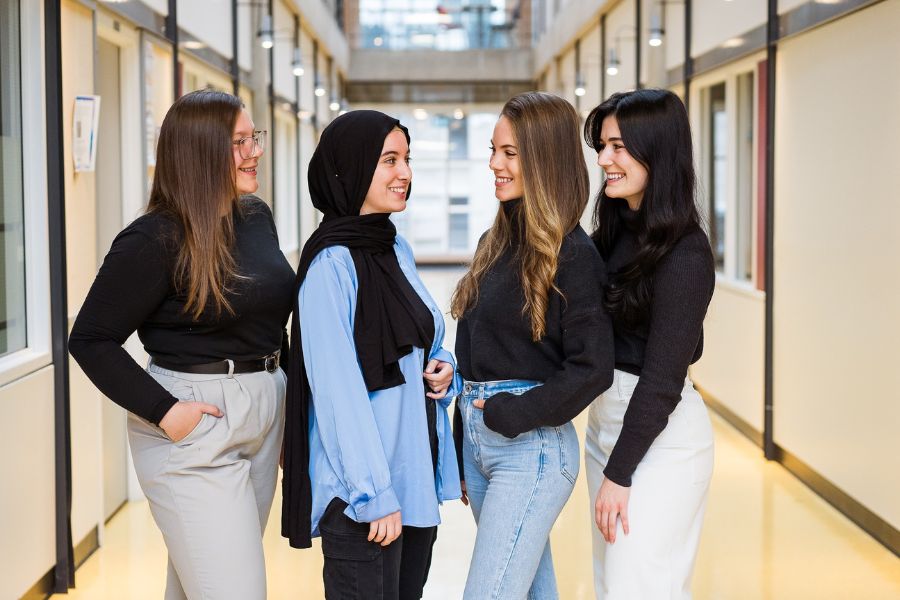 Group of four diverse TeamNutrition Dietitian smiling and chatting in a hallway