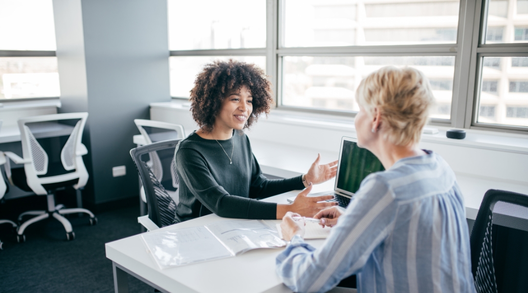 Two people talking at a table in an office