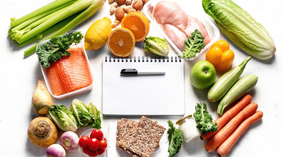 an open notepad surrounded by a variety of vegetables and fruits