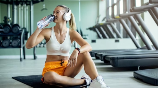 Femmes avec écouteurs qui boit une boisson durant son entrainement