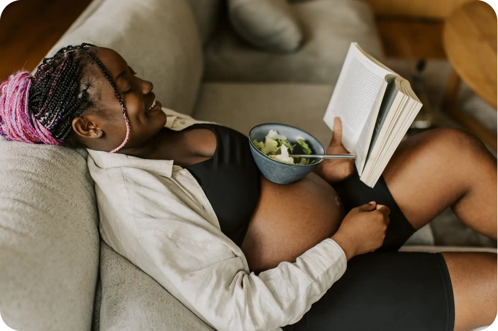 Pregnant woman reading a book with a salad