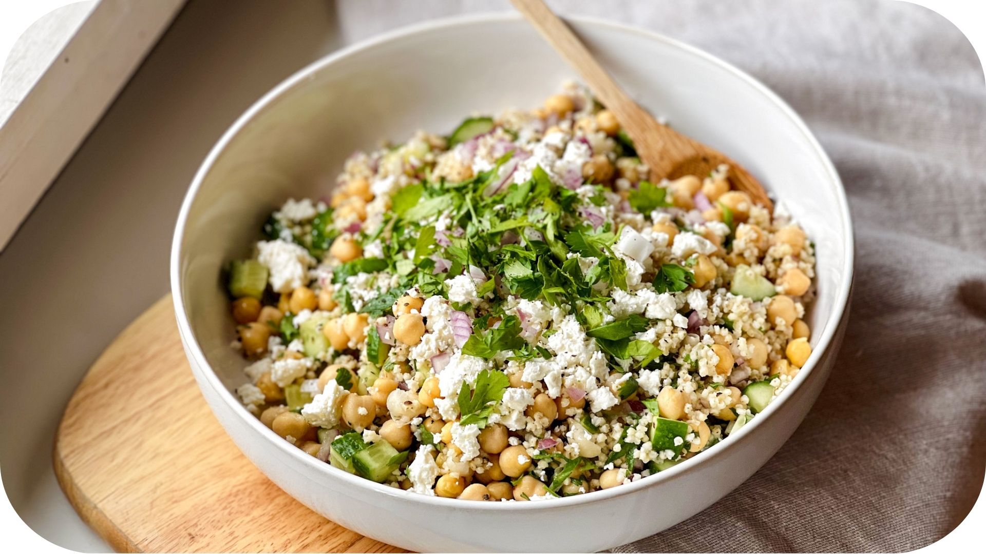 Bowl of Mediterranean quinoa salad with chickpeas, cucumber, feta cheese, red onion, and fresh parsley