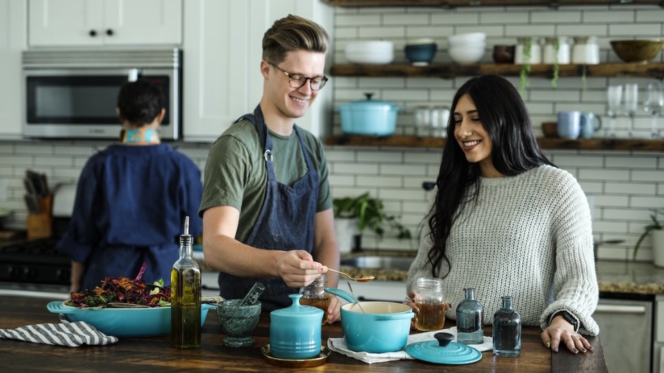 man and woman smiling as they cook