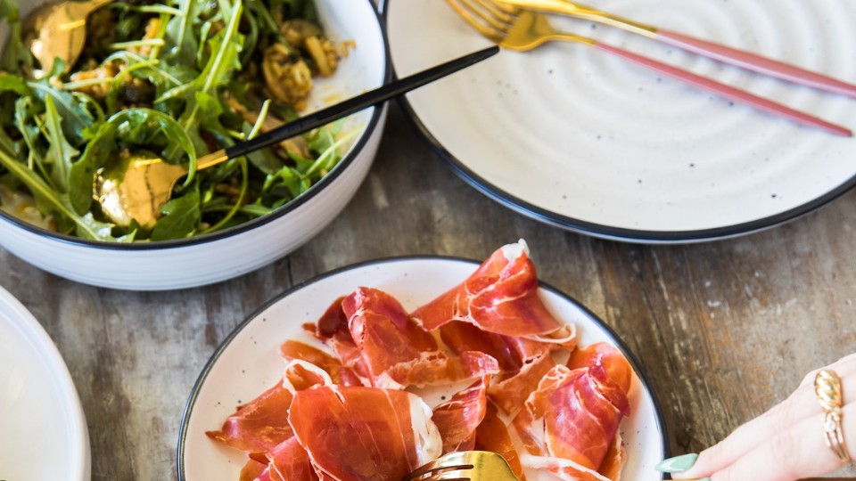 A plate of prosciutto and a plate of arugula
