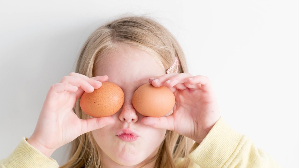 child hiding his eyes with eggs