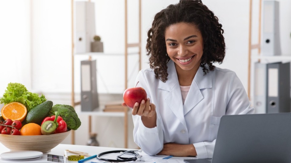 nutritionist-dietitian in her office presenting a fruit