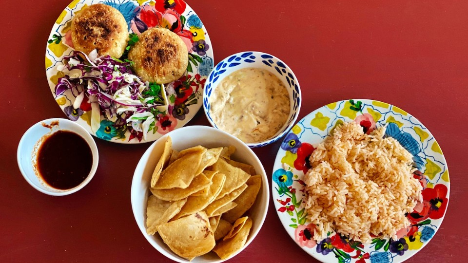 rice, patties and chips in dishes on a red background