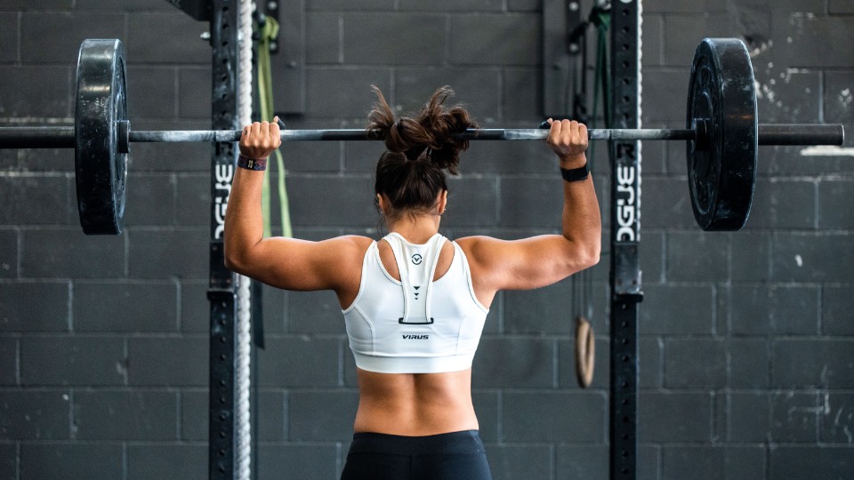 woman with muscular back lifting a dumbbell