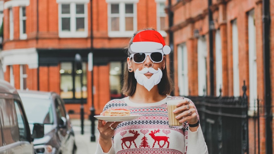 woman dressed as santa claus holding a glass of eggnog and a dessert