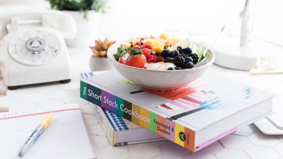 bowl of fruit on a pile of books