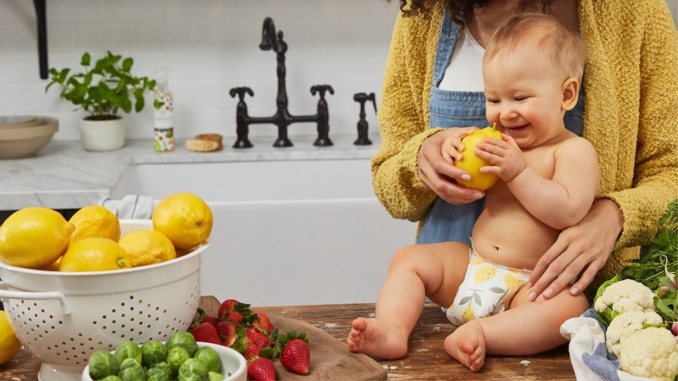 baby on the counter touching fruits