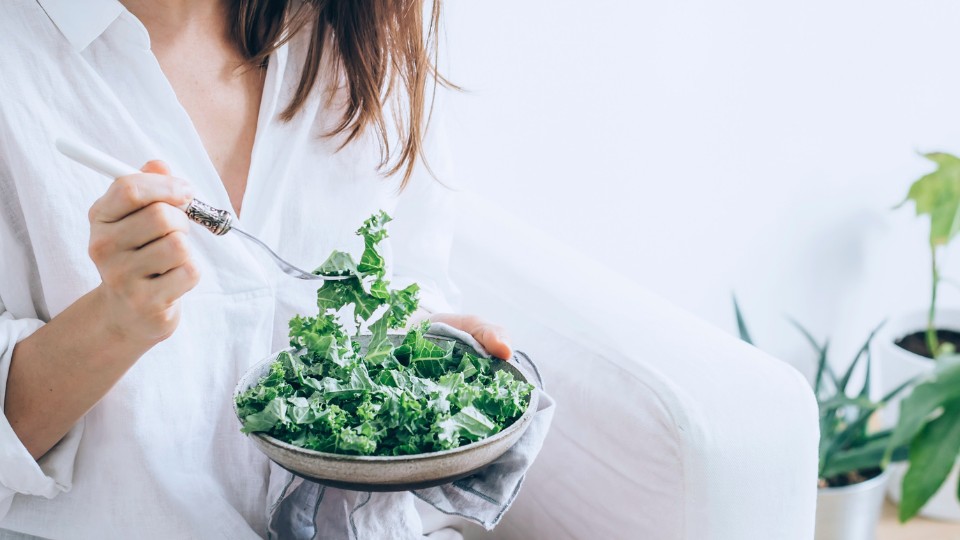 Girl dressed in white eating a kale salad