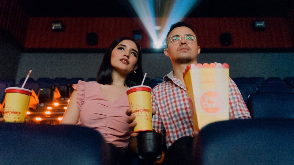 couple qui mange du popcorn avec des boissons gazeuses en écoutant un film au cinéma