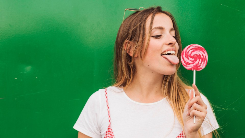 girl with a white t-shirt licking a candy, green background