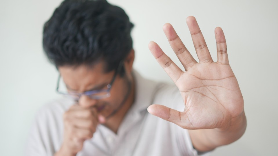 man in white sweater putting his hand in front of him