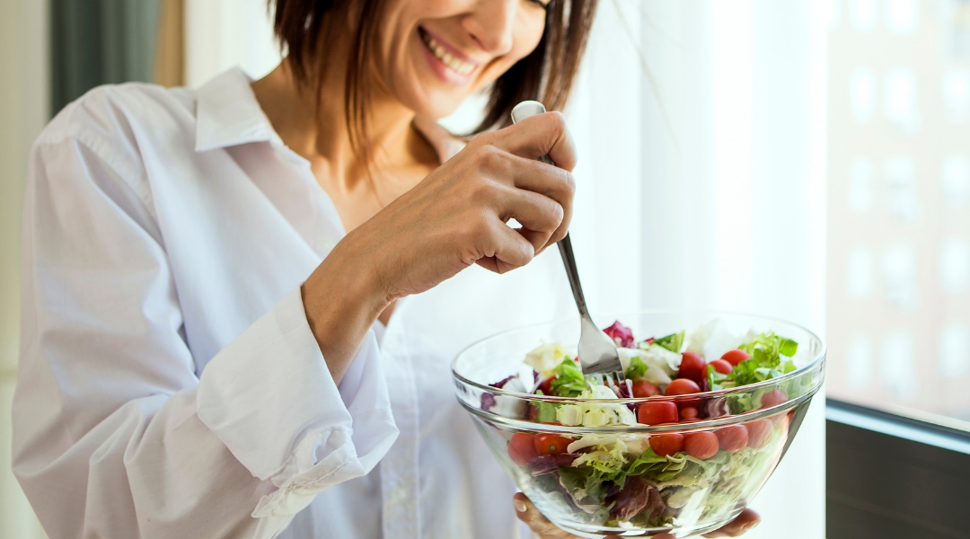 a person holding a bowl of salad in front of a window