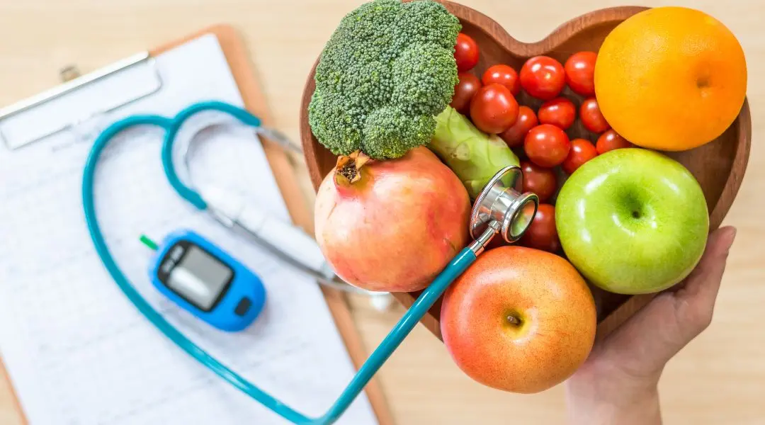 Triglycérides : des gestes concrets pour un taux plus sain. a person holding a stethoscope next to a bowl of fruits and vegetables