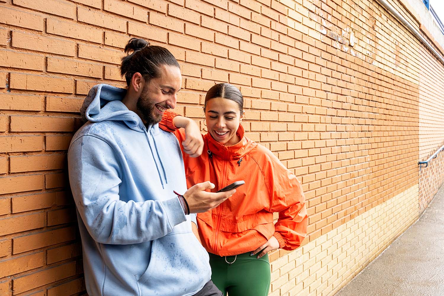 Deux amis souriants regardent un téléphone - Two smiling friends looking at a phone