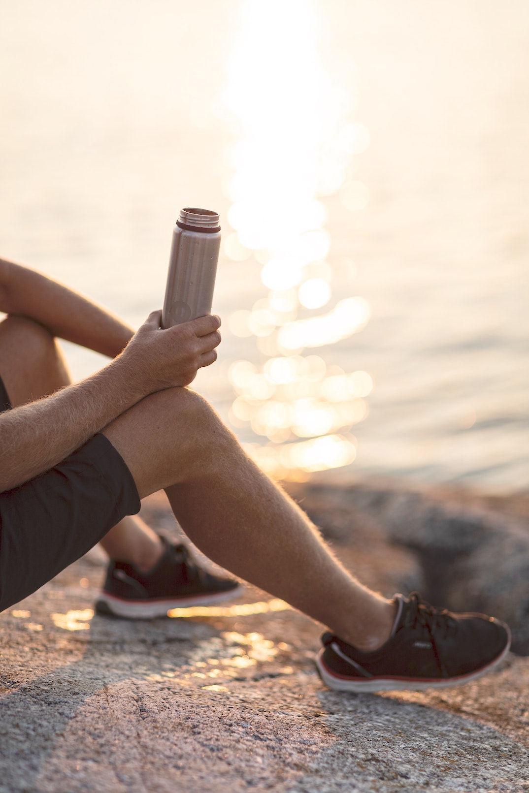 sportsman on the water's edge with his water bottle