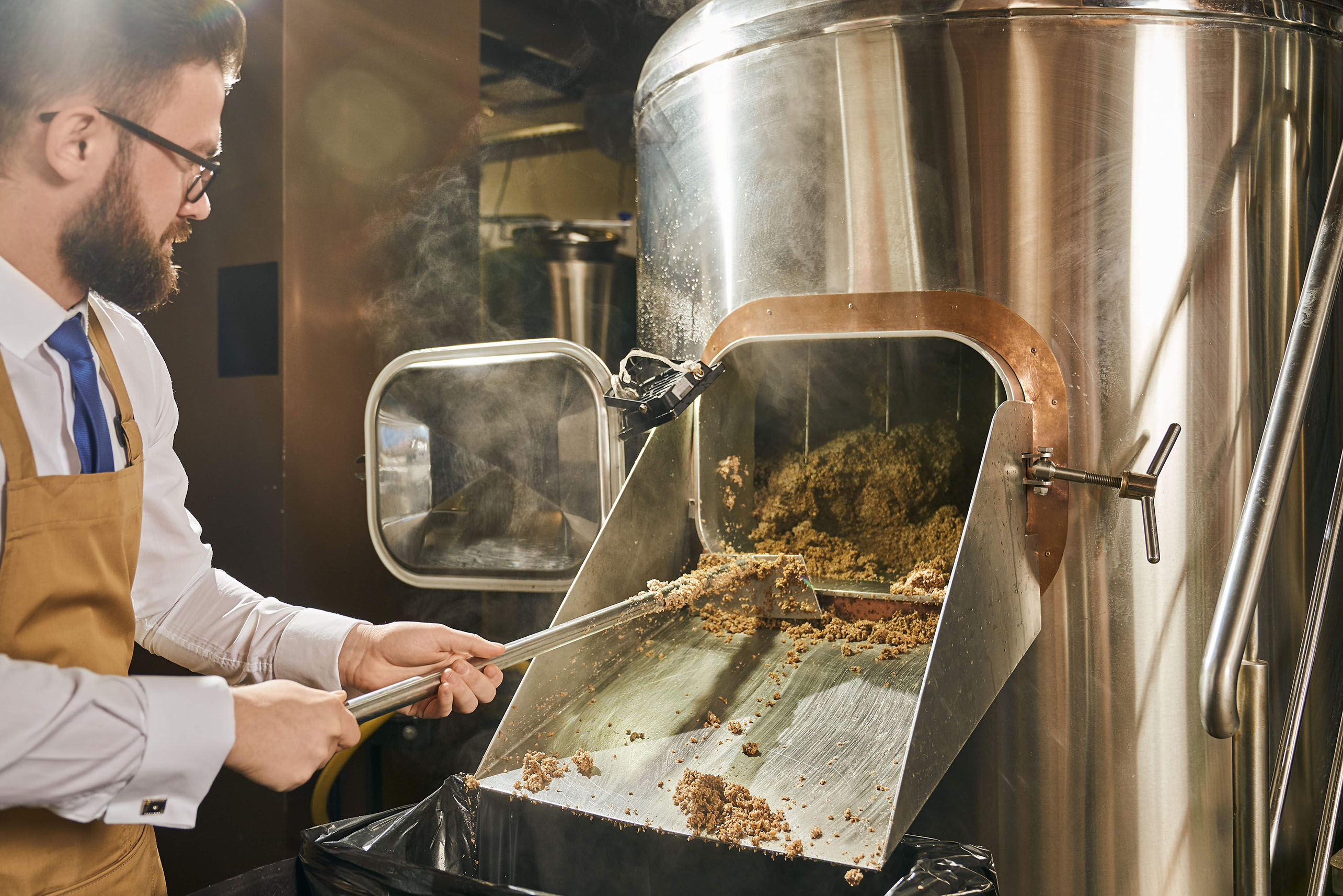 man taking the spent grains out of the brewing system