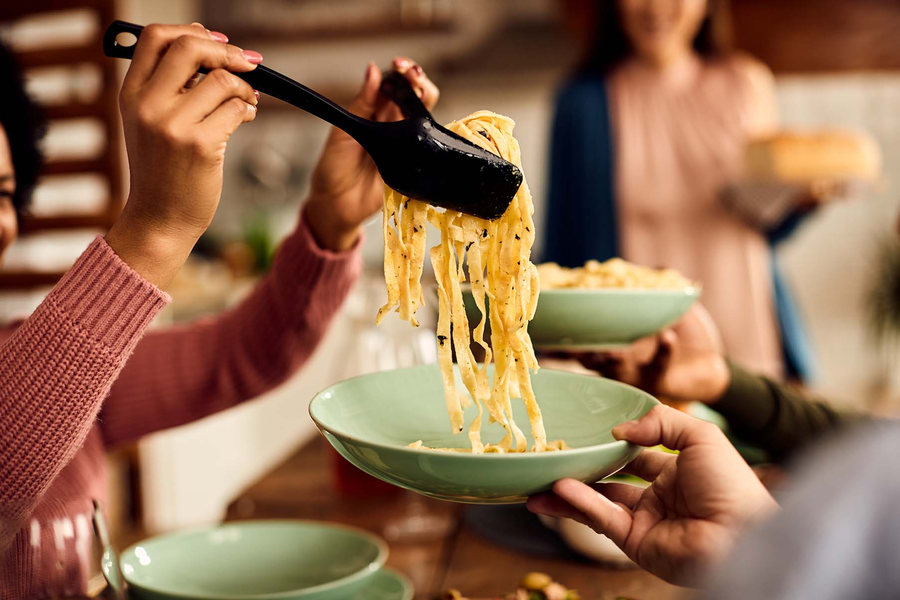 Gros plan d'une personne servant des pâtes fraîchement cuites - Close-up of a person serving freshly cooked pasta