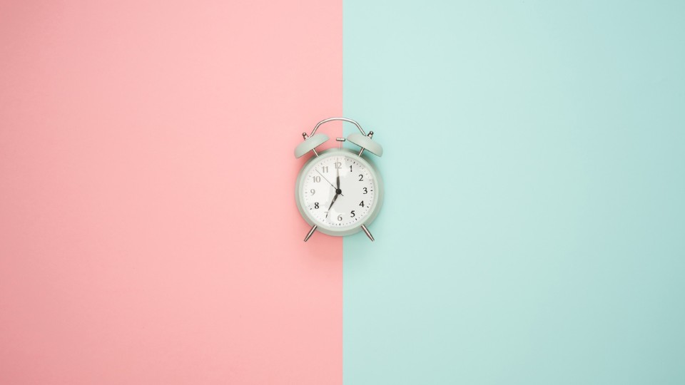 clock in the middle of a background pink and turquoise