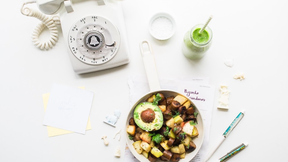 poêlée de légumes, smoothie et un téléphone sur une table blanche