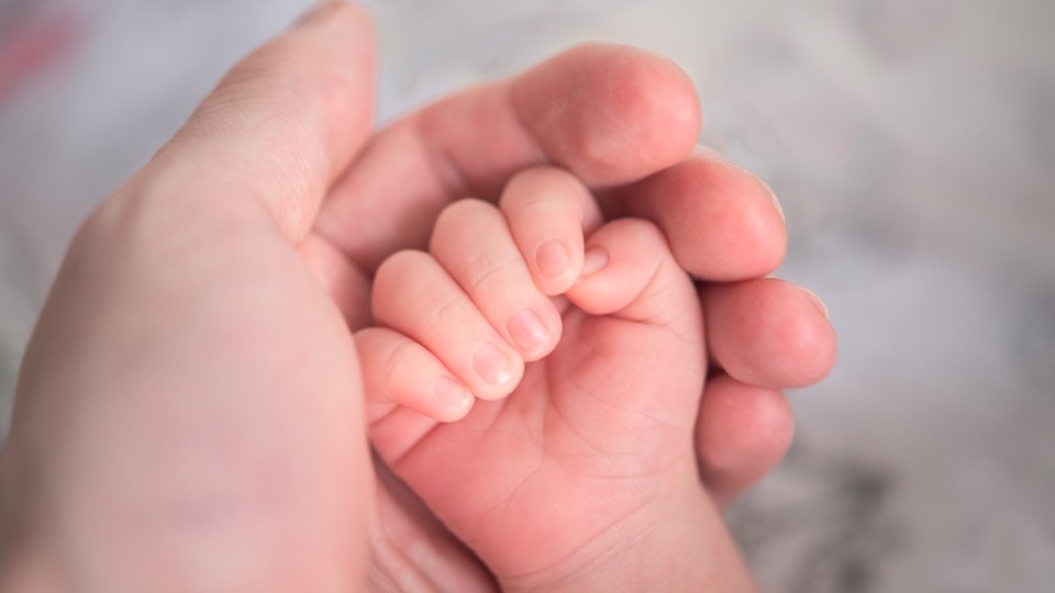 Hand of a baby in the hand of her mother