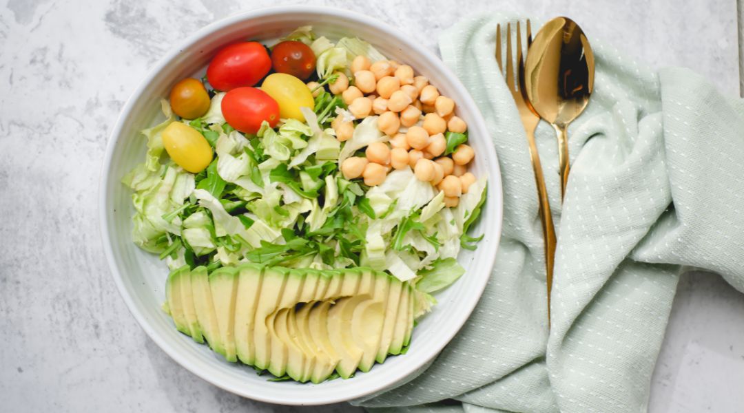 un bol de salade avec avocat, tomates et pois chiches