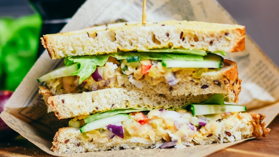 un sandwich coupé en deux dans un emballage papier