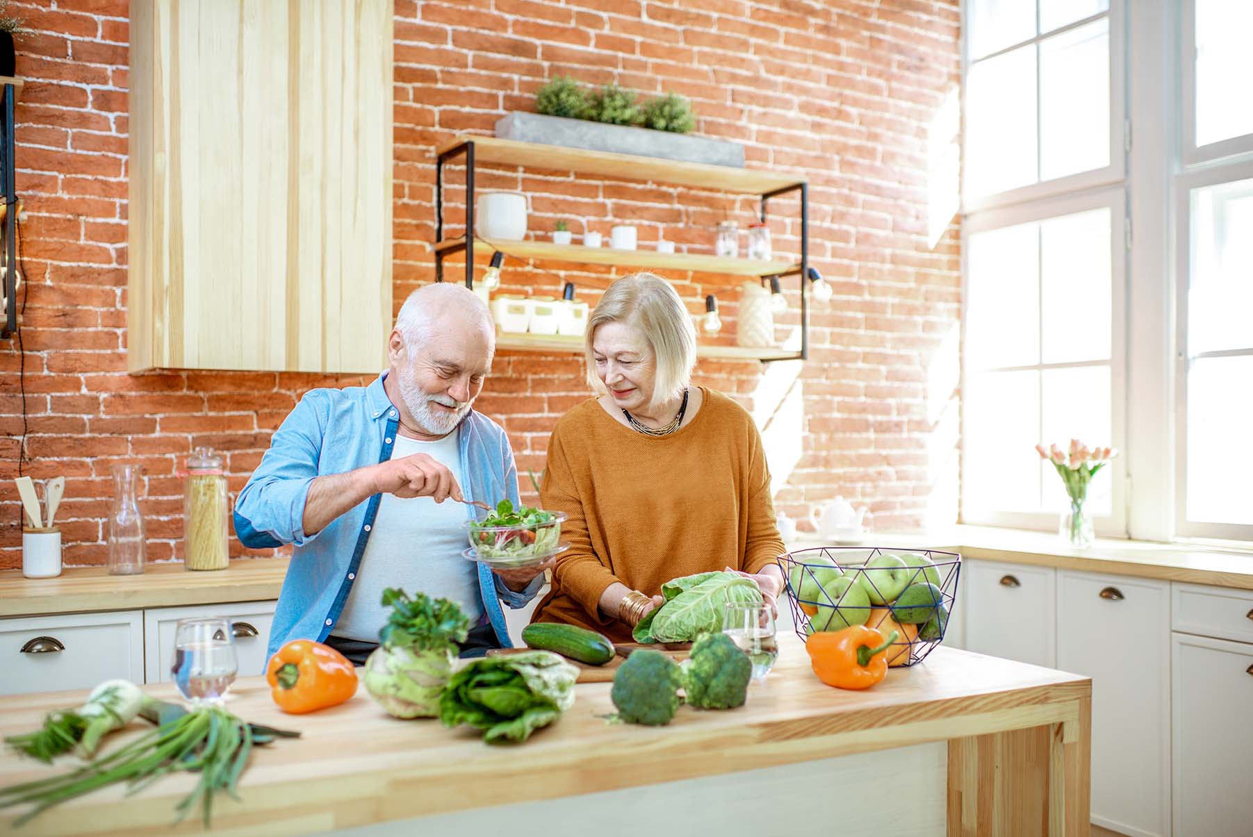 Couple senior préparant une salade ensemble dans une cuisine avec des légumes frais - Senior couple preparing a salad together in a kitchen with fresh vegetables