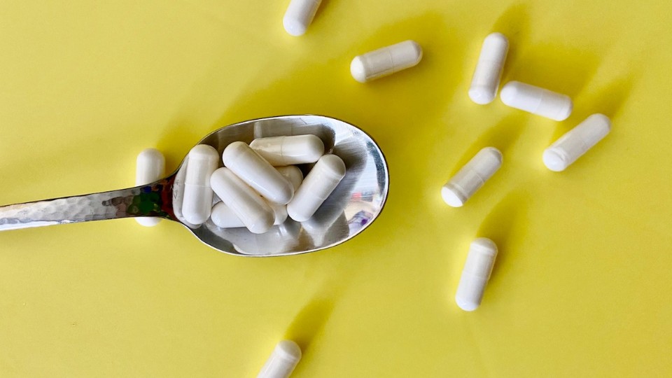 Supplements in a spoon on a yellow background