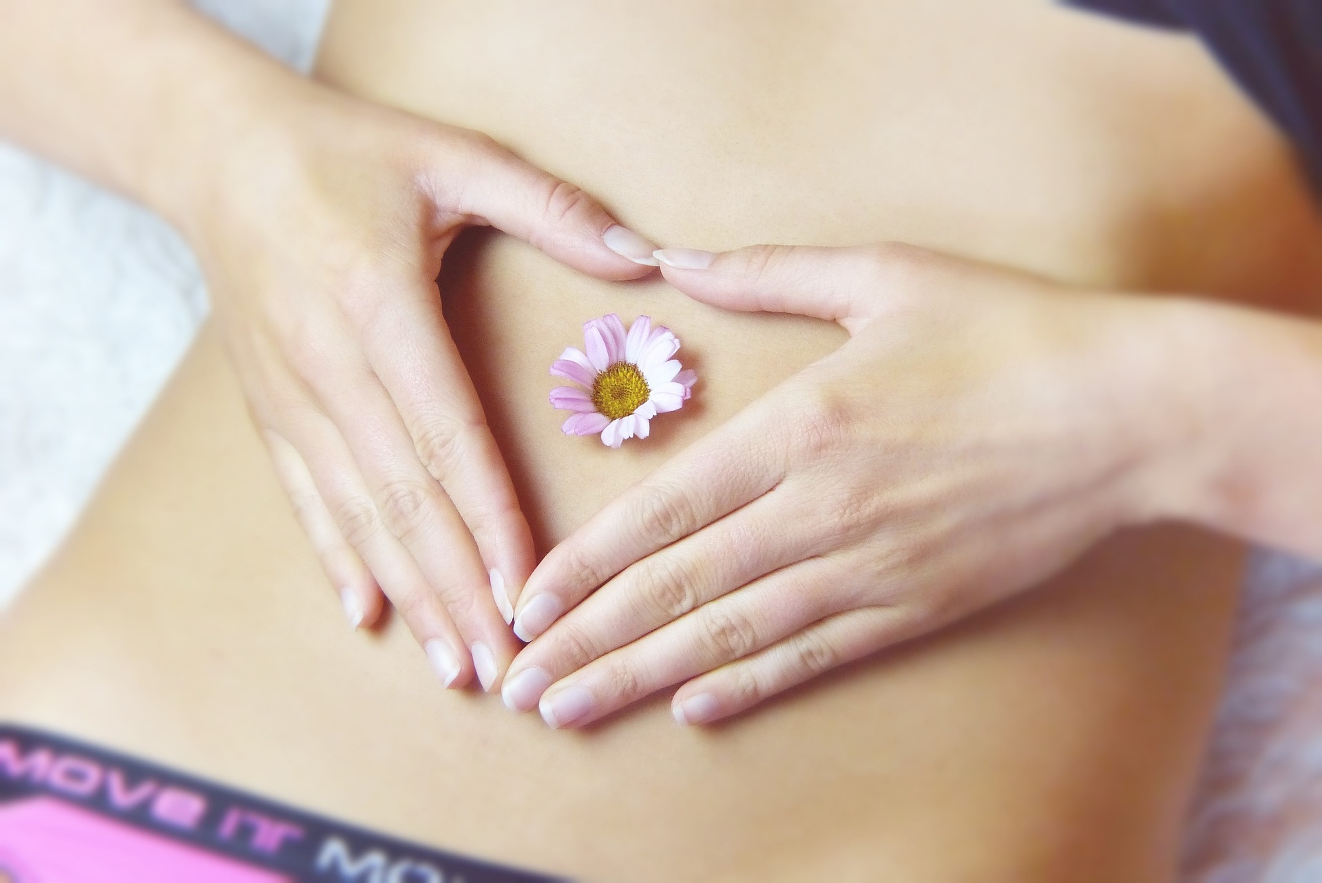 Hands making a heart on a belly