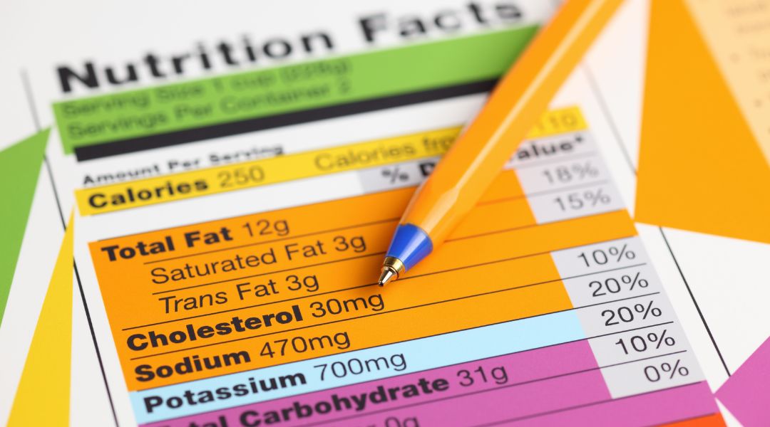 Close-up of a colorful nutrition facts label with a yellow pen placed diagonally across it