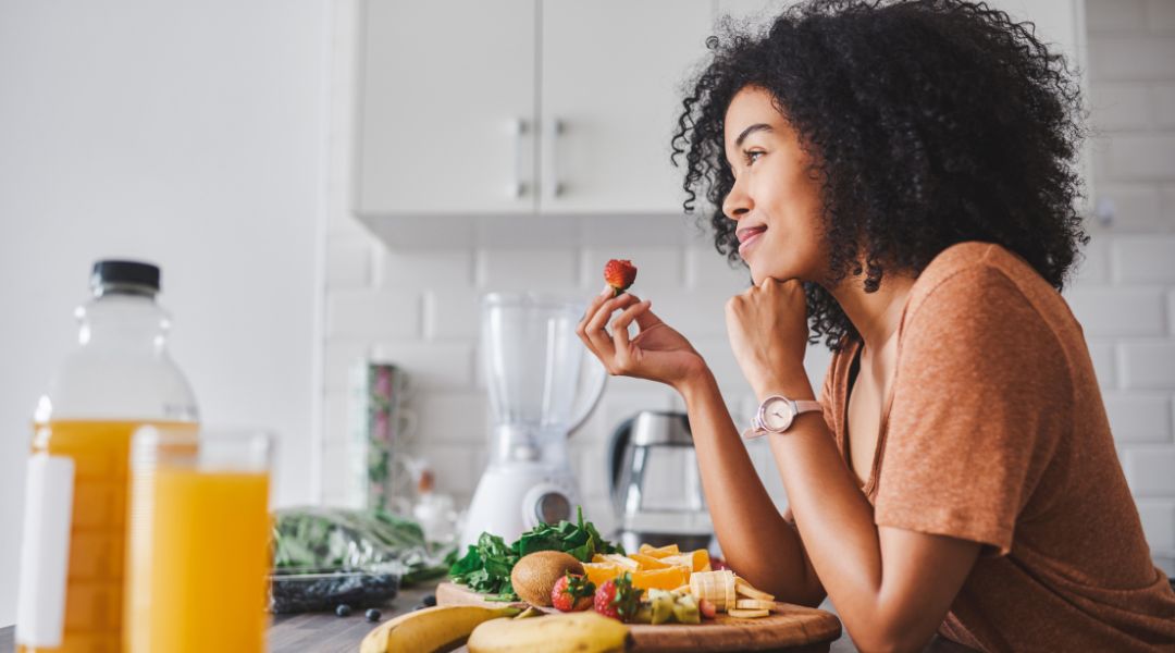 a woman eating a strawberry in her kitchen
