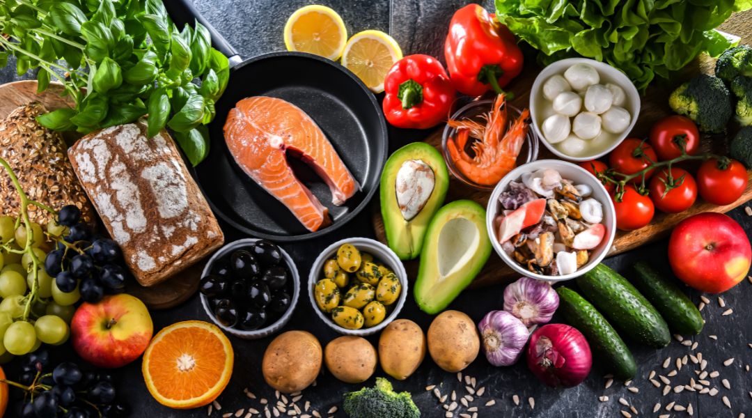 A colorful assortment of Mediterranean diet foods, including salmon, vegetables, fruits, and whole grains