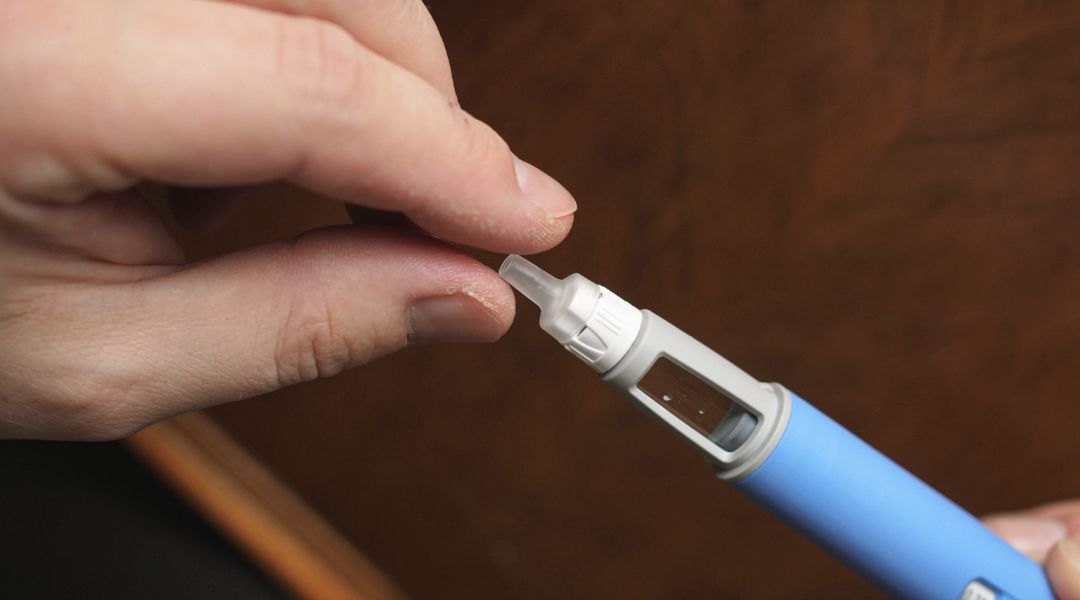 A person removing the cap from a semaglutide container