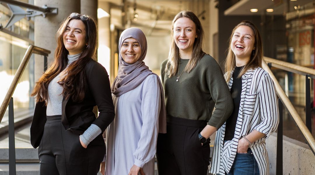 Four TeamNutrition Dietitians Nutritionists smiling confidently while standing together on an indoor staircase