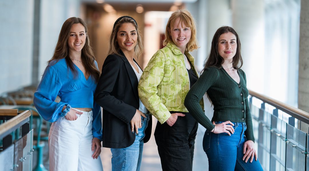 Four TeamNutrition Dietitians and Nutritionists stand together in a modern hallway, smiling and posing for the camera