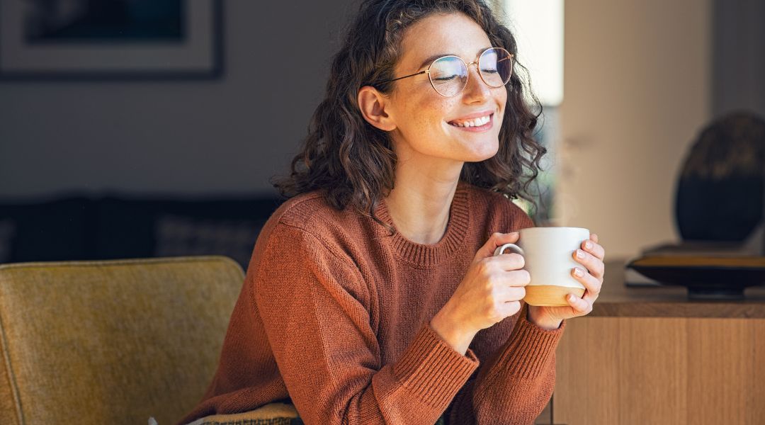 smiling person drinking coffee at home