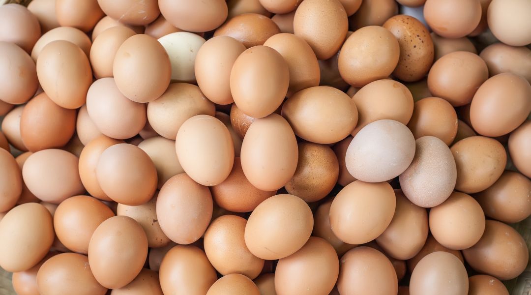 A large pile of brown eggs with slight variations in color and texture