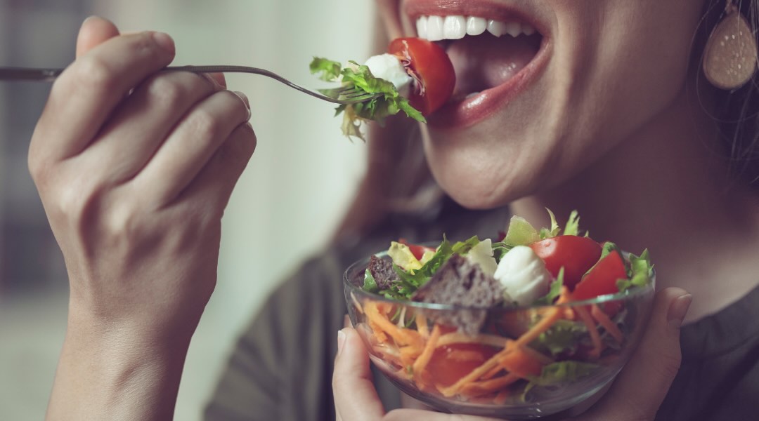 A person enjoys a fresh and colorful salad, made of crisp vegetables and nutritious ingredients.